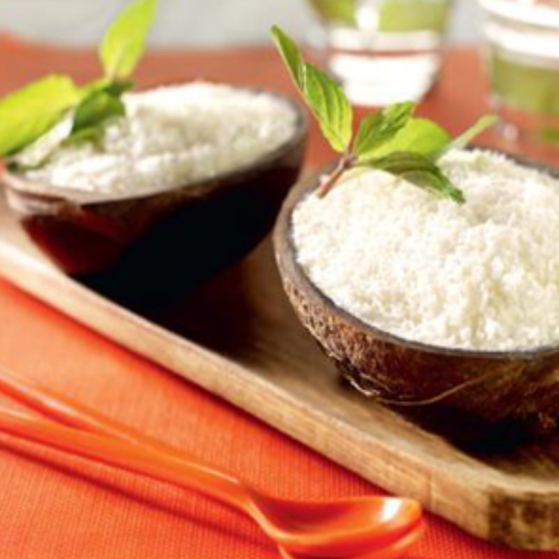 Crème glacée noix de coco avec noix de coco râpée, présentée dans une noix de coco givrée.